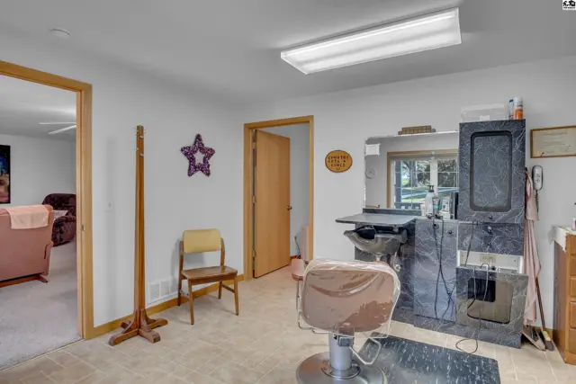 Salon space with a styling chair, shampoo sink, and bright overhead lighting.