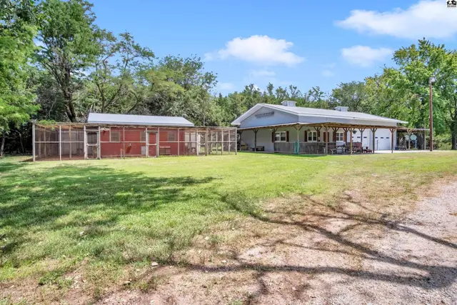 Spacious property features a light blue home with a covered porch and a large red chicken coop.
