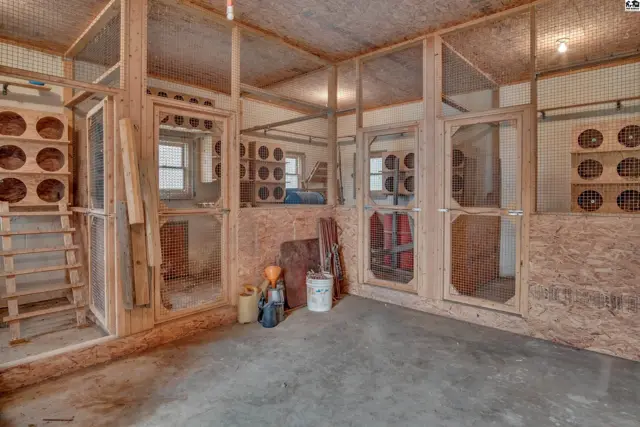Interior of a spacious chicken coop with wooden roosts, nesting boxes, and wire mesh enclosures.