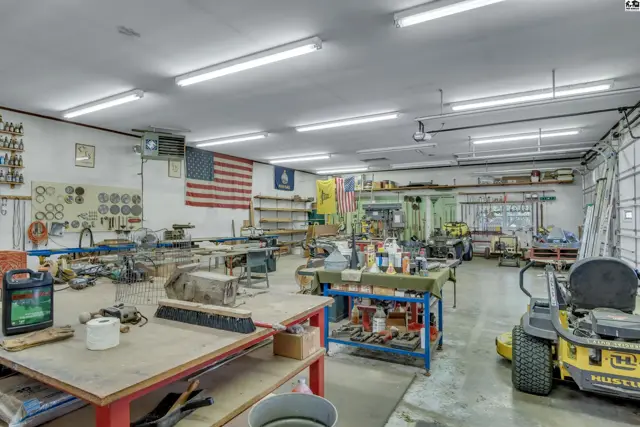 Spacious workshop with workbenches, tools, storage, and a zero-turn mower.