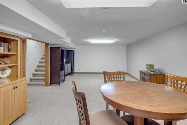 Spacious finished basement with carpet, wood cabinetry, and a dining set.