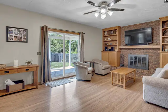 Spacious living room with a brick fireplace, built-in bookshelves, and sliding glass doors to the backyard.