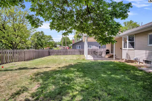 Spacious backyard with a wooden deck, privacy fence, and mature trees.