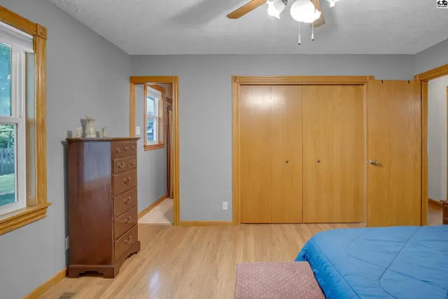 Spacious bedroom with light wood floors, gray walls, and large oak closet doors.
