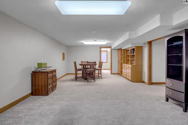 Spacious finished basement with carpet, wood cabinetry, and a dining set.