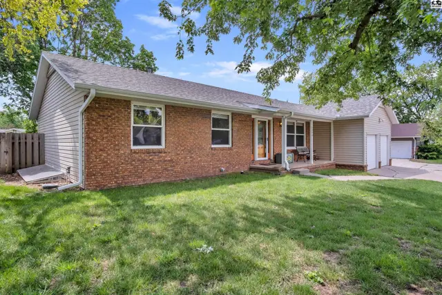 Brick and vinyl ranch home with a covered porch and attached garage.