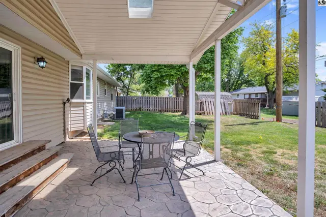 Covered patio with stamped concrete, metal patio set, and backyard view.