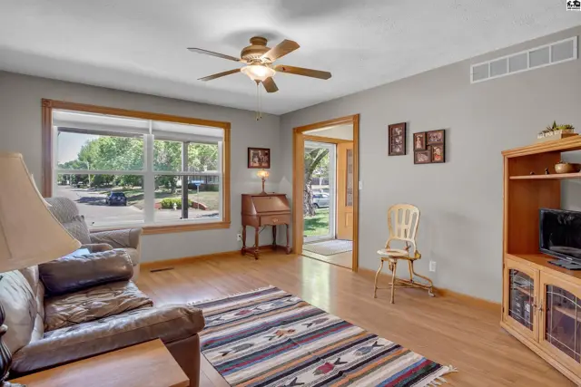 Living room with hardwood floors, a large window, and a leather sofa.