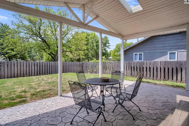 Covered patio with stamped concrete, outdoor dining set, and fenced backyard.