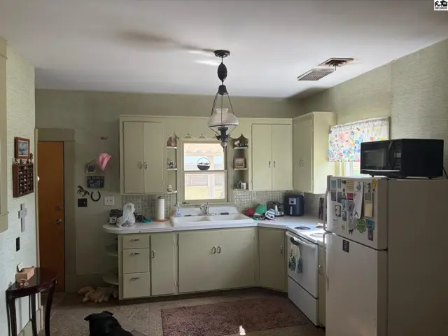 Light green cabinets and countertops in a retro kitchen with a white stove and refrigerator.
