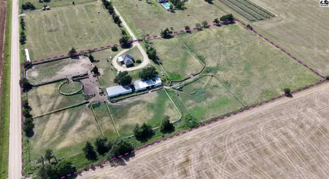 Aerial view of a sprawling rural property with a house, barn, stables, and riding arena.