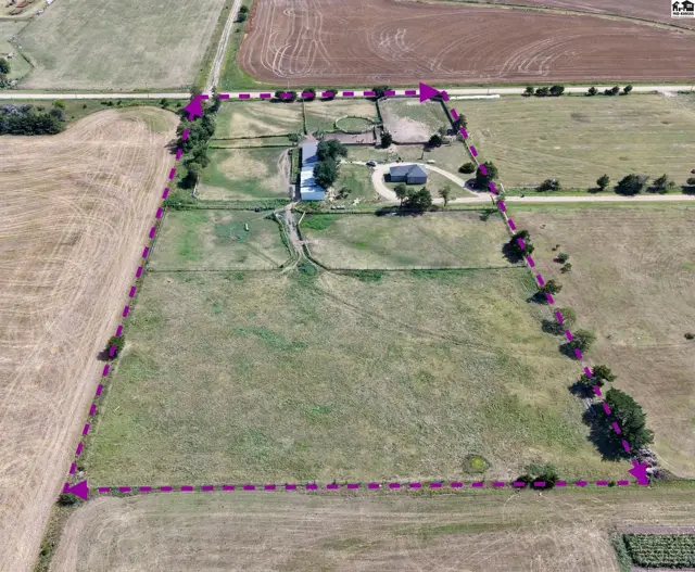 Aerial view of a sprawling rural property with a house, barns, and fenced pastures.