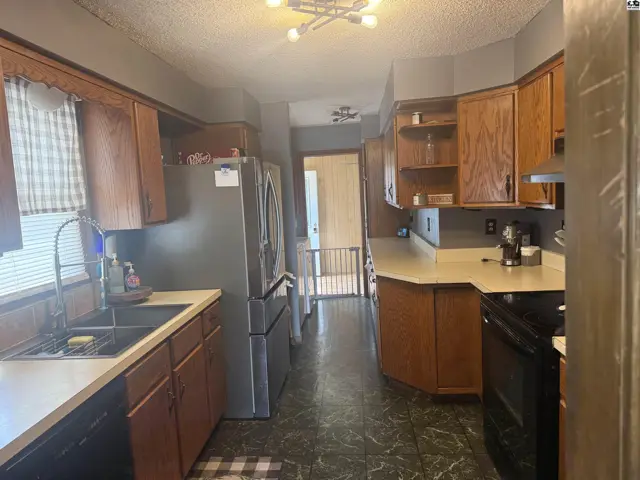 Spacious kitchen with oak cabinets, stainless steel appliances, and patterned flooring.