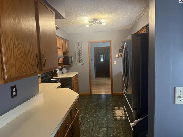 Kitchen with oak cabinets, white countertops, dark green patterned floor, and stainless steel appliances.