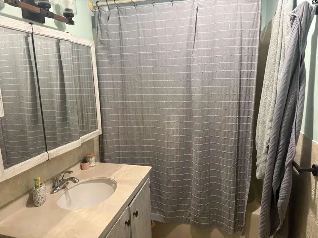 Bathroom with a vanity, sink, mirrored cabinet, and a striped shower curtain.