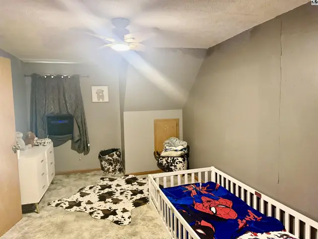 Child's bedroom with gray walls, cow print rug, and a white crib.