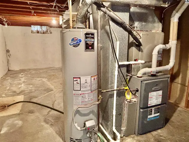 Basement utility area with water heater, furnace, and concrete floor.