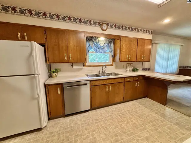 Spacious kitchen with light oak cabinets, white countertops, stainless steel appliances, and patterned flooring.