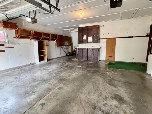 Spacious garage with concrete floor, wood cabinetry, and overhead door opener.