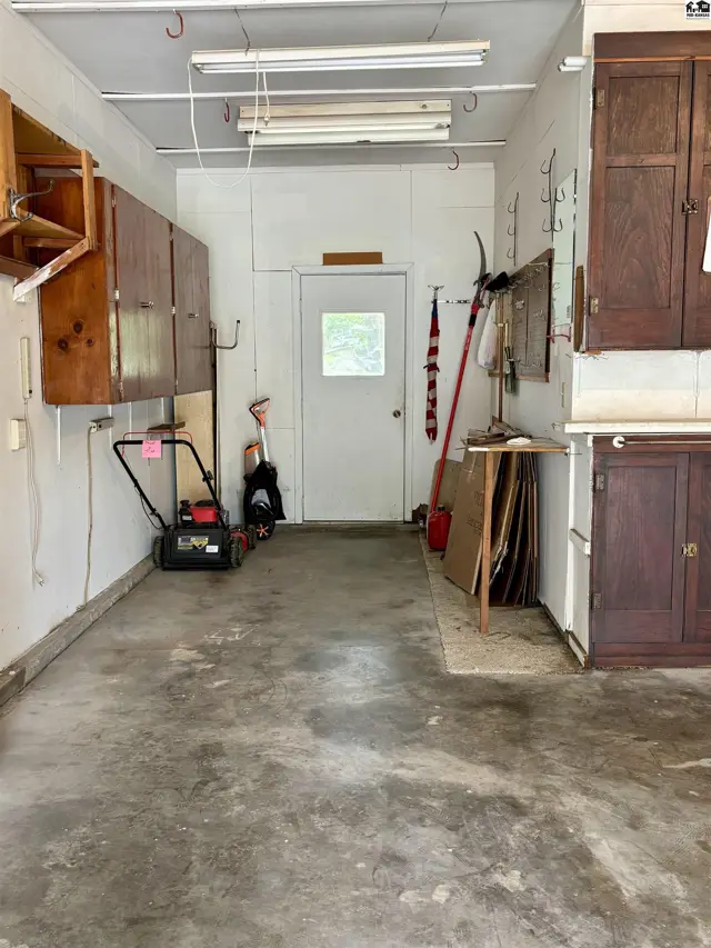 Spacious garage with concrete floor, white walls, and ample wooden cabinetry for storage.