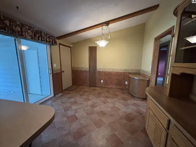 Dining area with vaulted ceiling, exposed beam, tiled floor, and built-in cabinetry.