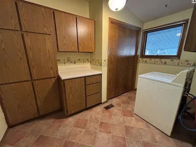 Kitchen with light yellow walls, oak cabinets, white countertops, and a beige washing machine.