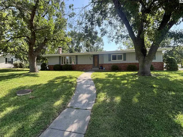 Ranch-style home with light gray siding, brick accents, and mature trees in a well-kept yard.