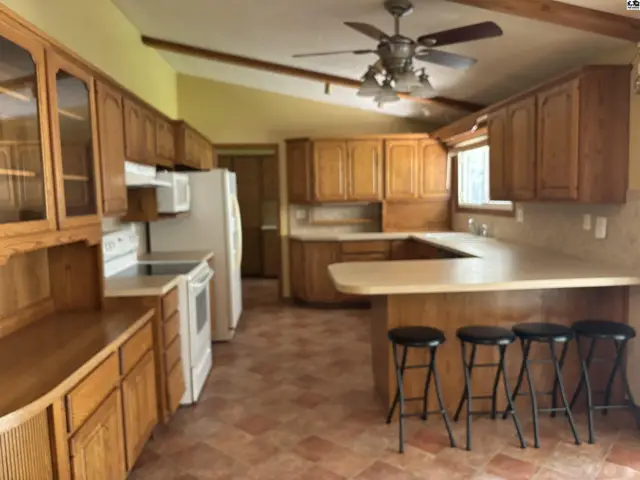 Spacious kitchen with light wood cabinets, white appliances, and a large island with seating.