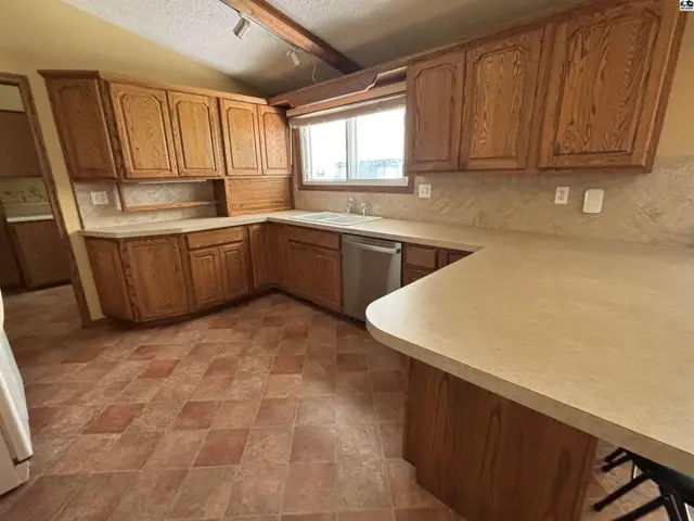 Spacious kitchen with oak cabinets, laminate countertops, and tiled flooring.