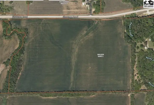 Aerial view of a large, cleared agricultural field bordered by trees and a creek.