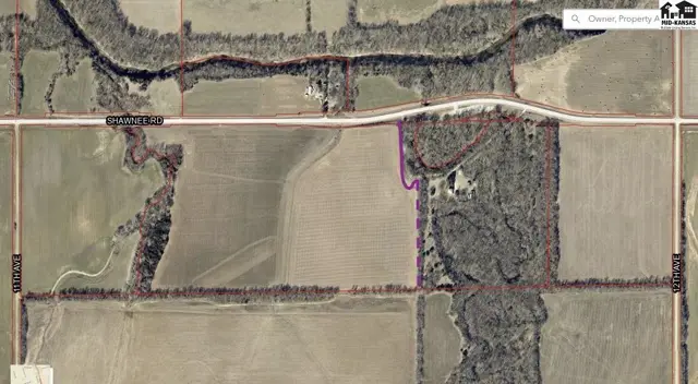 Aerial view shows a large parcel of land with fields, wooded areas, and a road.