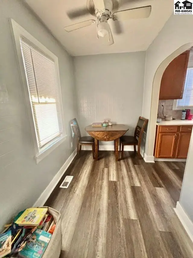 Cozy dining nook with a round table, two chairs, and wood-look flooring, opening to the kitchen.