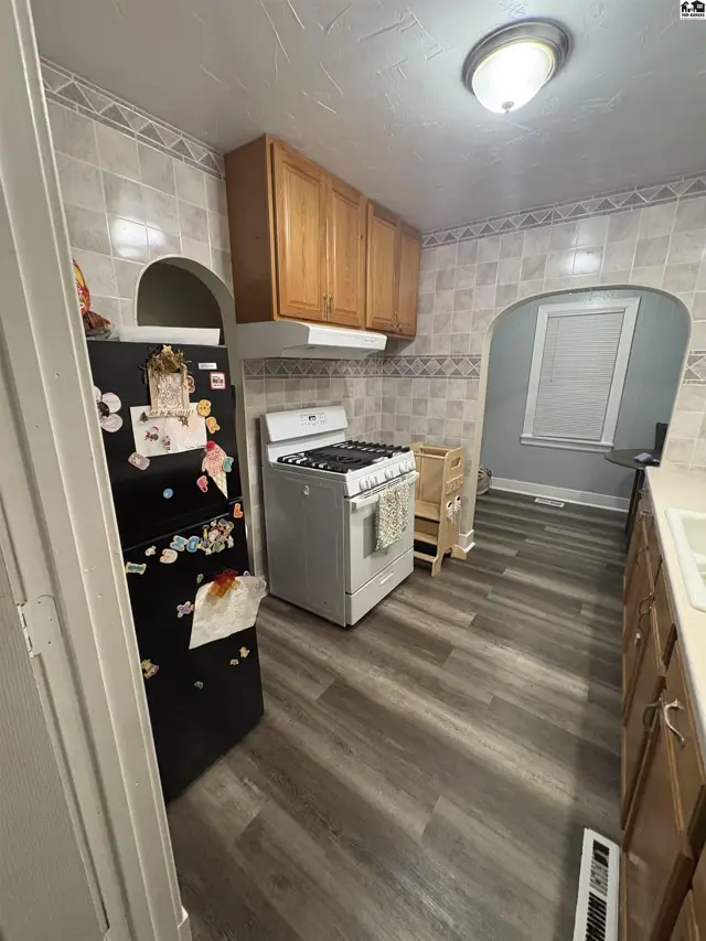 This kitchen features wood cabinetry, a gas range, and tiled backsplash.