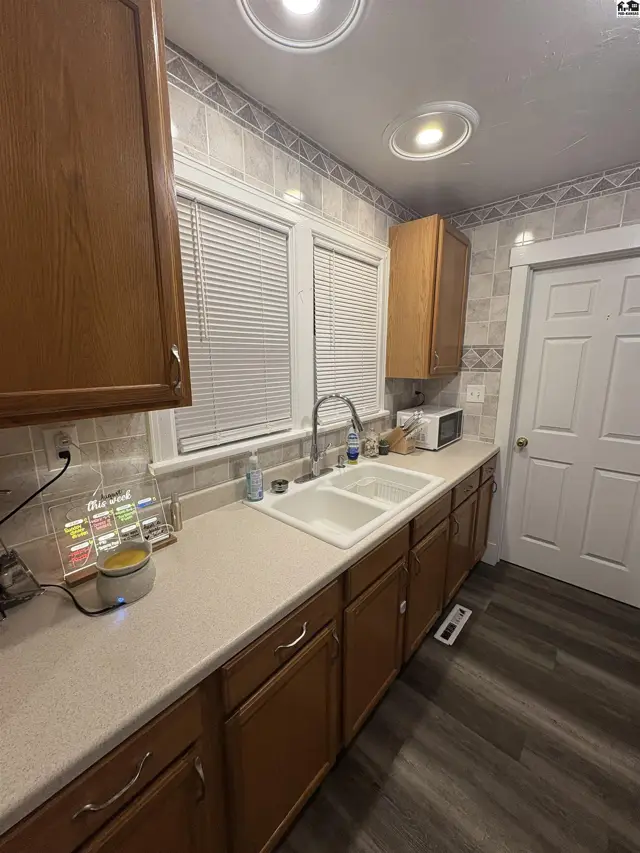 This kitchen features wood cabinetry, a double sink, and tiled backsplash.