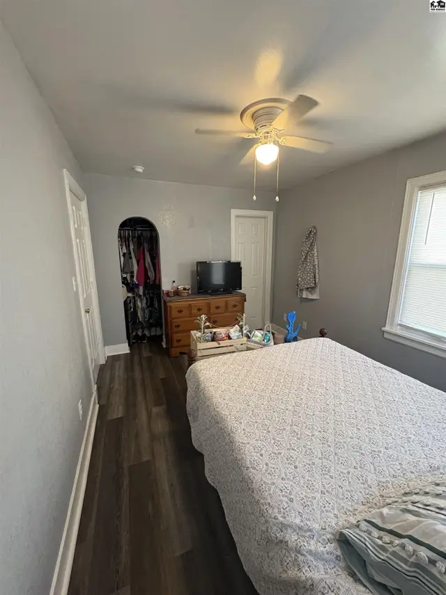 This bedroom features a ceiling fan, wood-look flooring, and a closet with built-in shelving.