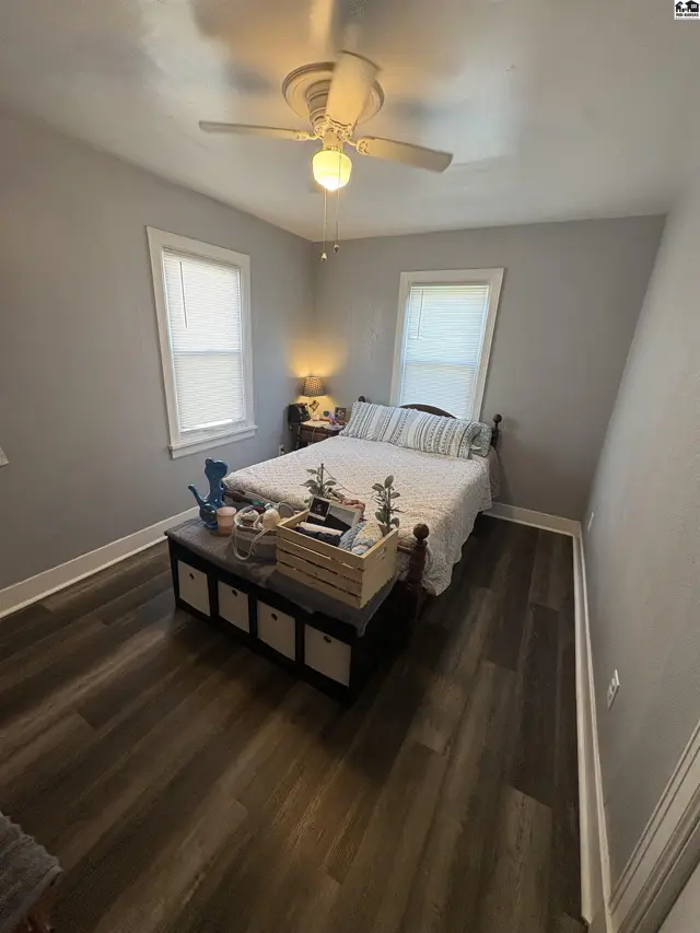 This bedroom features a queen-size bed, wood-look flooring, and a ceiling fan.