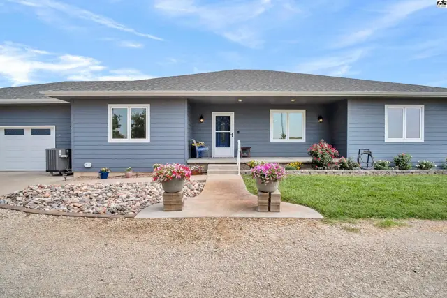 Blue siding ranch home with a welcoming walkway, manicured landscaping, and a detached garage.
