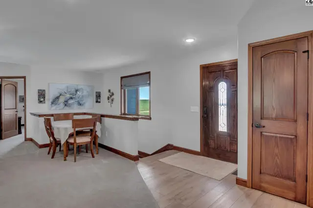 Spacious entryway with a dining area, featuring a wooden front door and warm wood trim.
