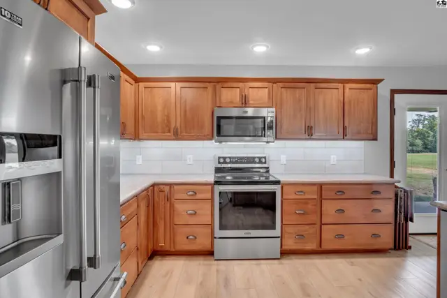 Spacious kitchen with light wood cabinets, stainless steel appliances, white subway tile backsplash, and light wood floors.