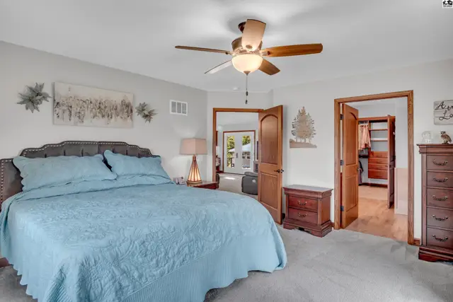 Spacious master bedroom with a king-size bed, plush carpet, and access to a walk-in closet.