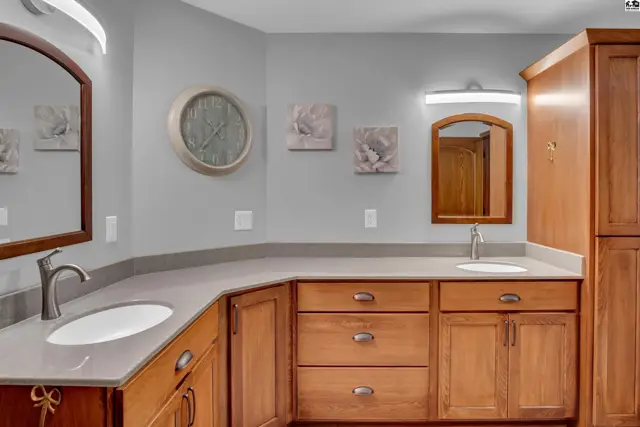 Spacious bathroom vanity with dual sinks, quartz countertops, and warm wood cabinetry.