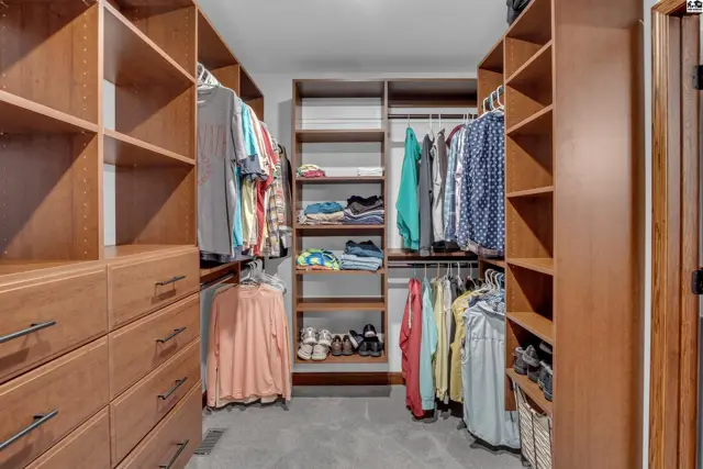 Spacious walk-in closet with custom wood shelving, drawers, and hanging rods.