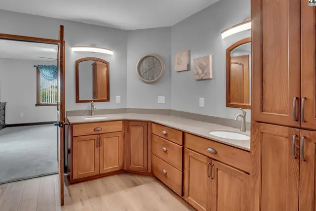 Spacious bathroom vanity with dual sinks, light wood cabinets, and neutral countertops.