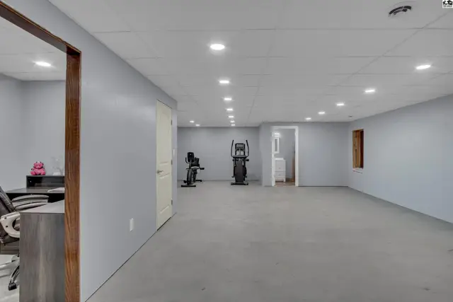 Spacious finished basement with gray flooring, white doors, and exercise equipment.