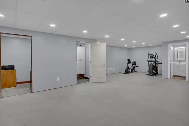 Spacious finished basement with exercise equipment, a closet, and a bathroom vanity.