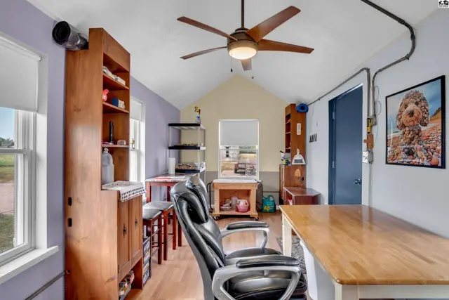 Bright room with wood floors, built-in shelving, a desk, and a ceiling fan.