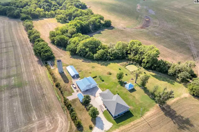 Aerial view of a rural property with a house, barn, silo, and surrounding fields.