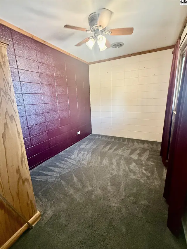 This room features textured purple and cream walls, carpeted floor, and a ceiling fan.
