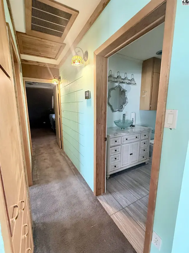 Hallway with wood accents and doors leading to rooms, including a bathroom with a vanity.
