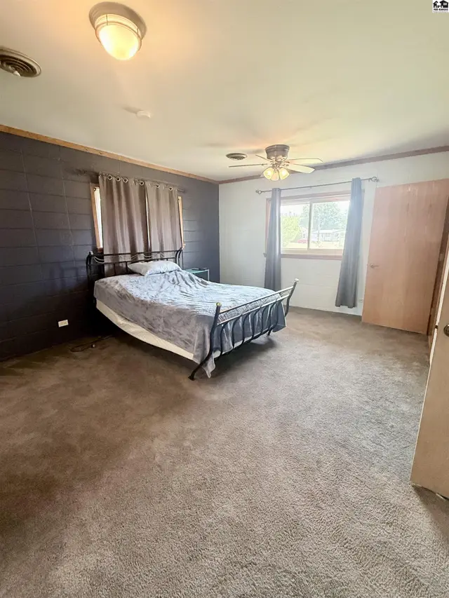 Spacious bedroom with carpet, ceiling fan, and large window.